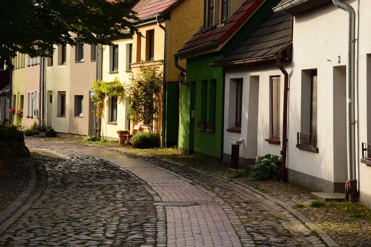 Eine gepflasterte Wohnstraße verläuft zwischen kleinen Häusern