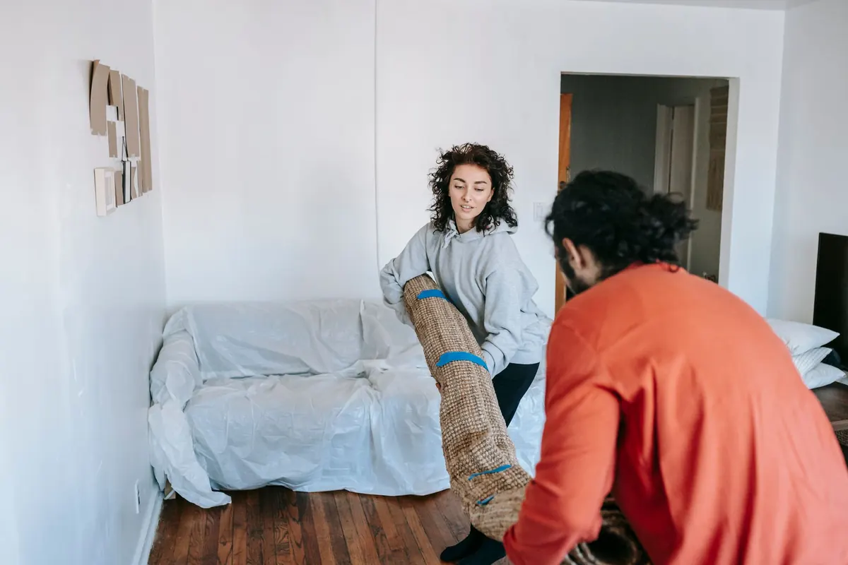 Mehrere Helfer decken ein Sofa zum Schutz für den Transport ab