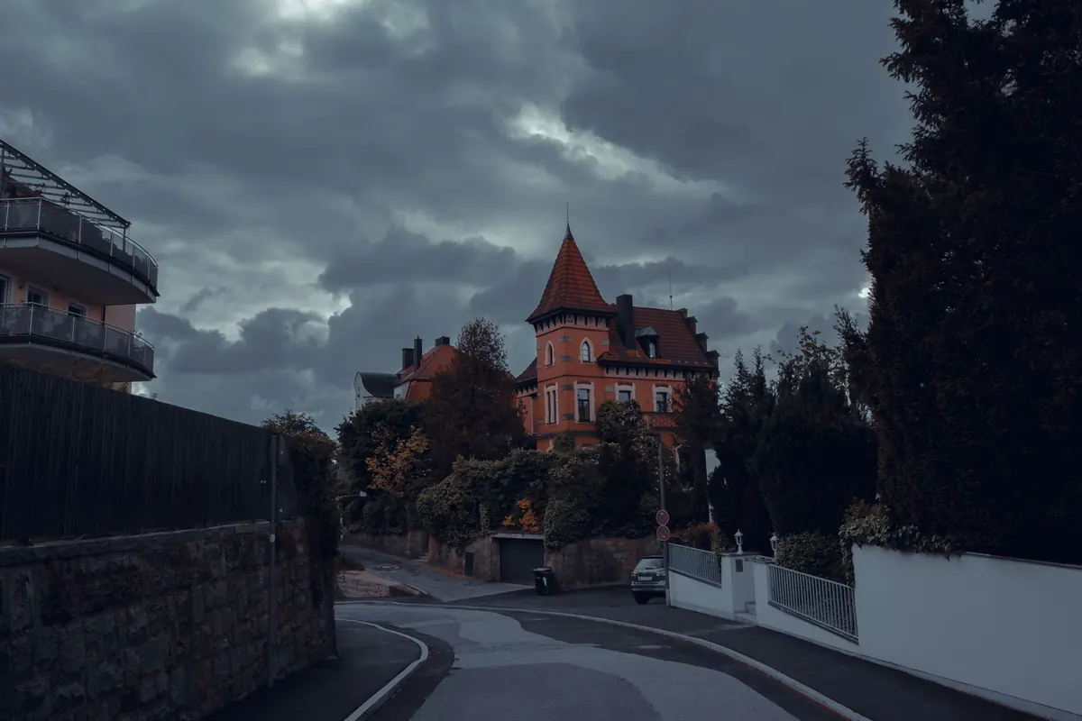 Eine kurvige Straße führt an einem Wohnhaus mit Turm vorbei