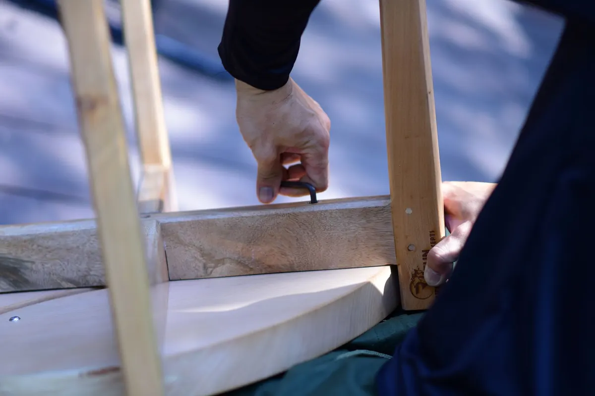 Hände setzen ein Möbelstück auf einer geschützten Arbeitsfläche zusammen