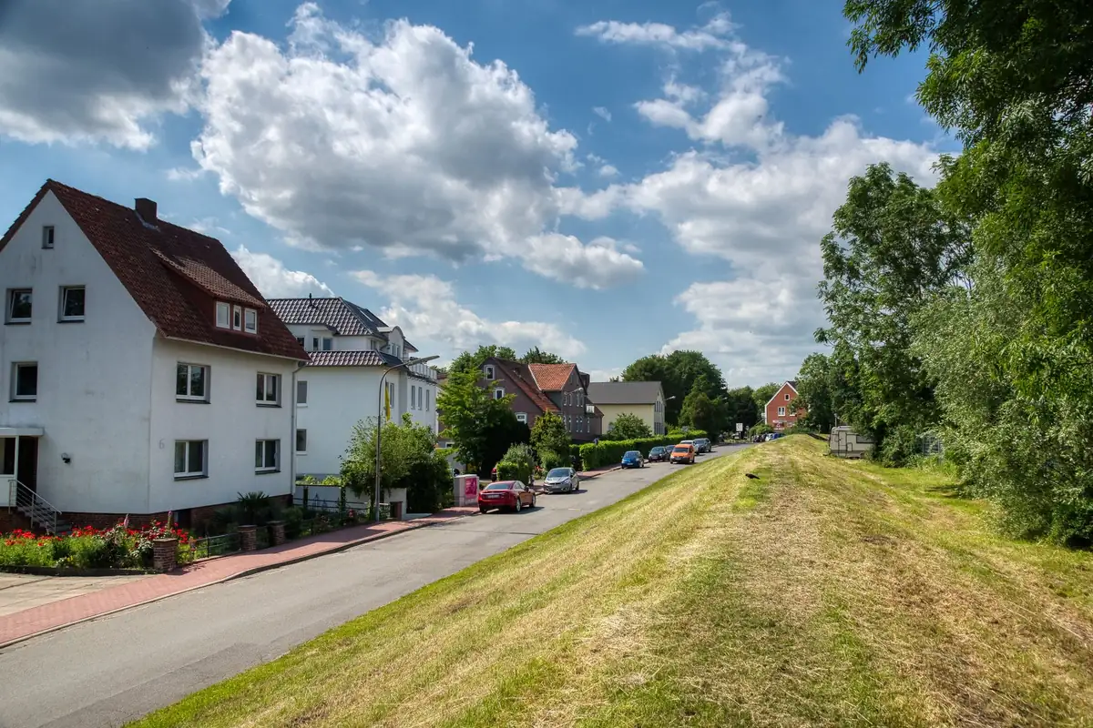 Eine Wohnstraße führt an Häusern und einer Grünfläche entlang