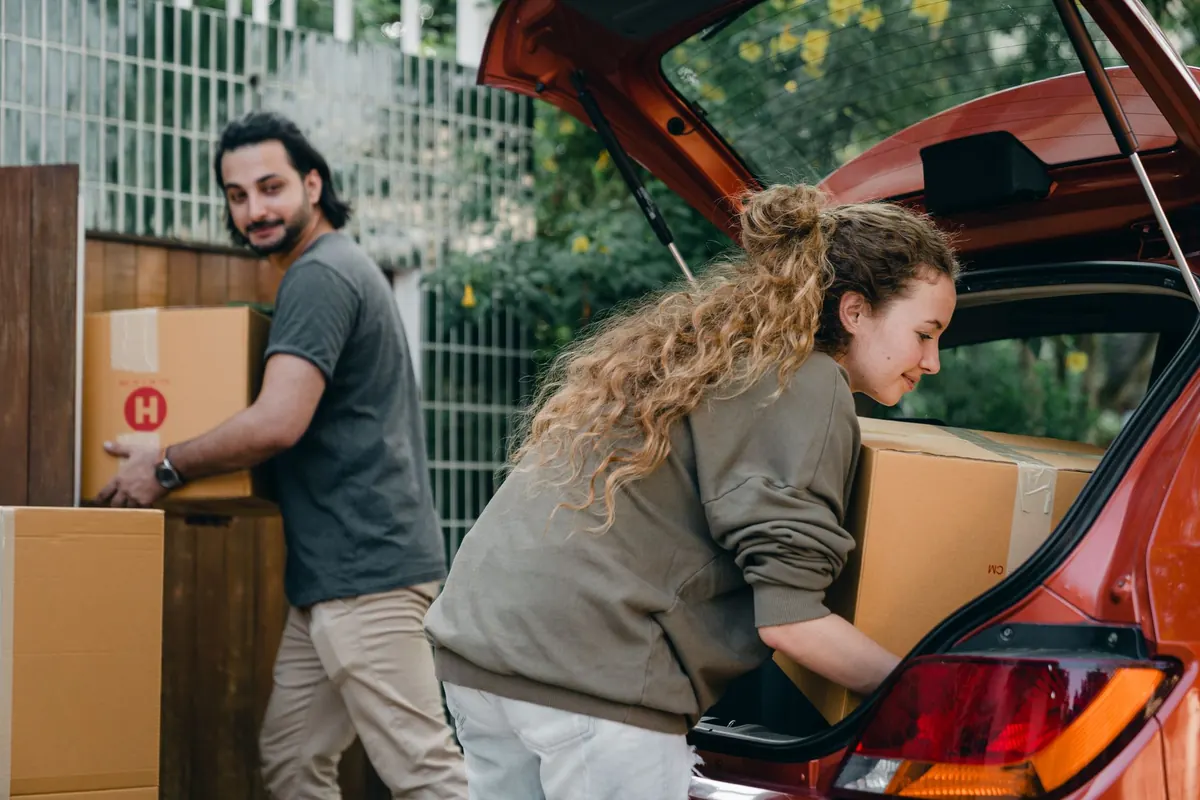 Ein Paar lädt Umzugskartons in den Kofferraum eines Autos